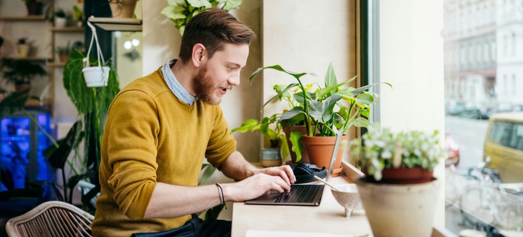 Freelancer working on his laptop in a bright, modern cafe.